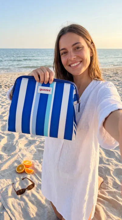 A smiling woman taking a selfie on the beach holding the cooler bag